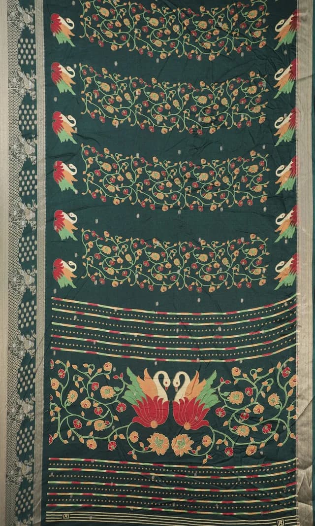 A dark green saree with swan and floral motifs photographed flat, cropped so only the fabric fills the frame